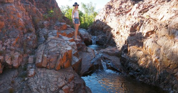 woman standing at edge on cascading waterfall in Litchfield national park