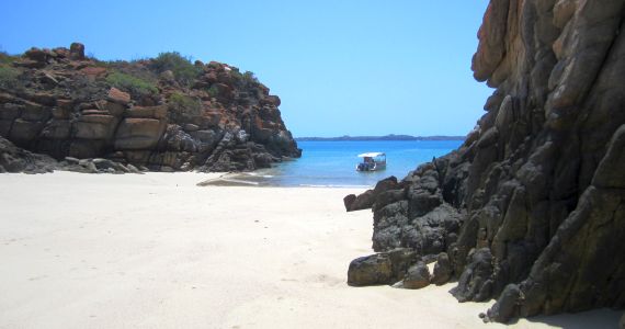 small boat leaving isolated beach off island on the Dampier Peninsula